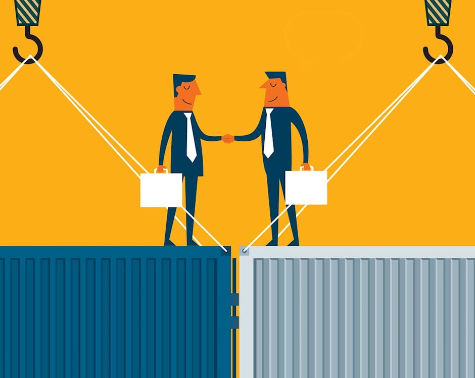 Businessmen shaking hands atop shipping containers