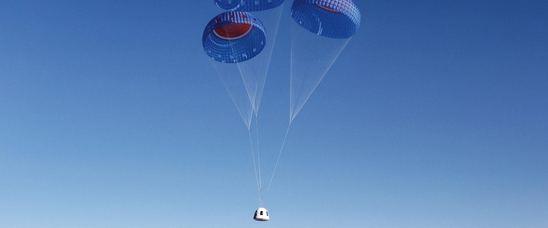A space pod in the sky with three small colorful parachutes attached