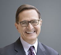 A headshot of Steve Kaplan against a gray background
