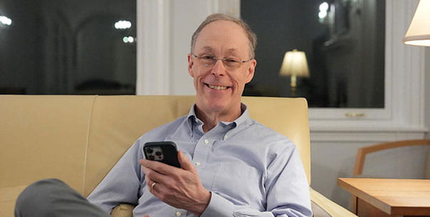 Doug Diamond sitting on couch holding cell phone