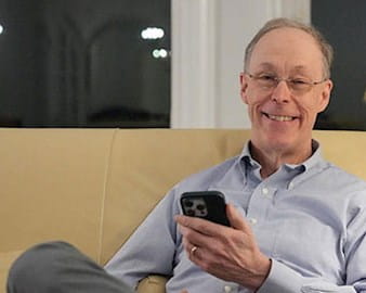 Doug Diamond sitting on couch holding cell phone