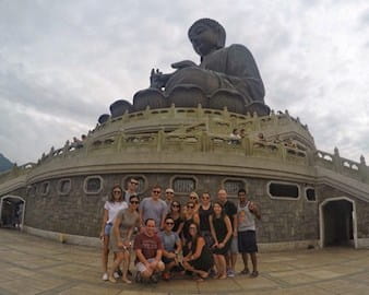 Group of Chicago Booth students pose in front of large Buddha monument in Hong Kong.
