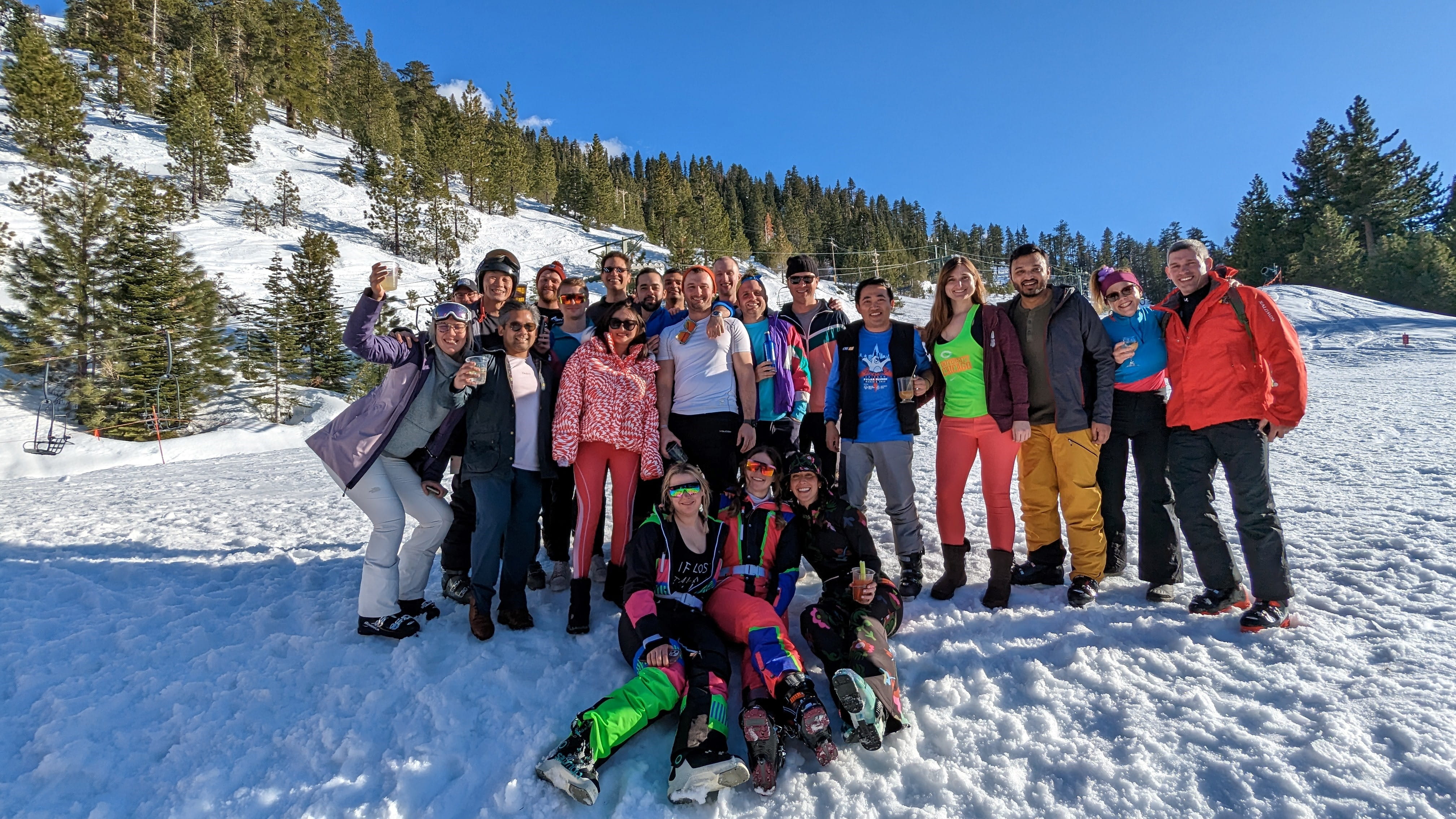 Group of about 20 Booth students in winter apparel outside with a snowy background posing together 