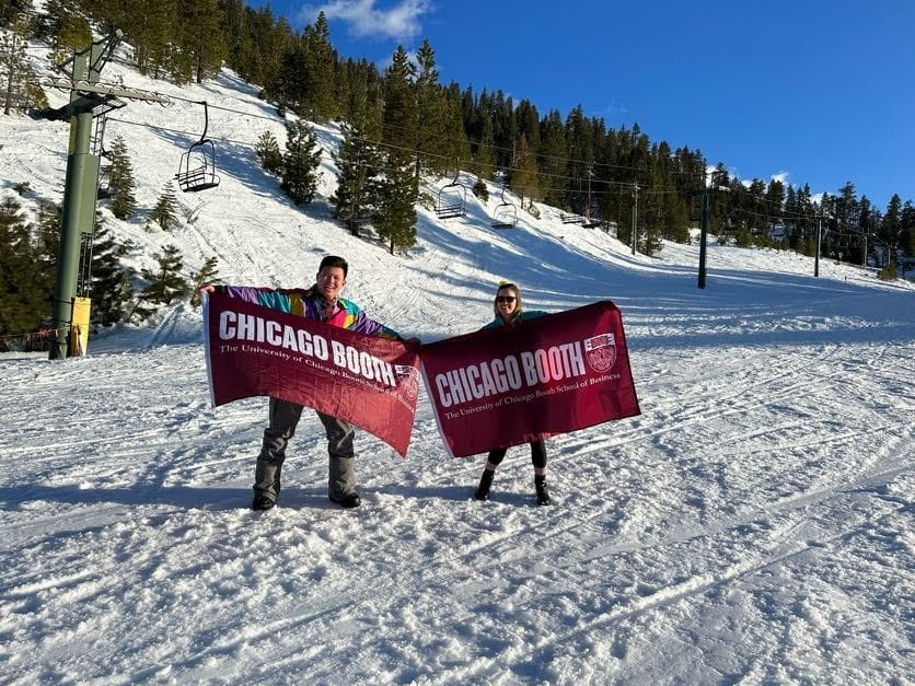 Two Boothies holding up Booth flags outside with snowy background on Evening Weekend Ski Trip