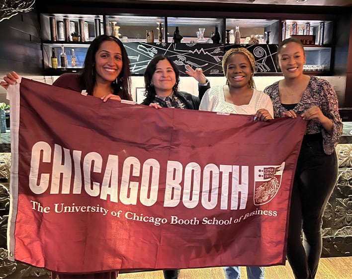 Boothies posing with Chicago Booth flag 