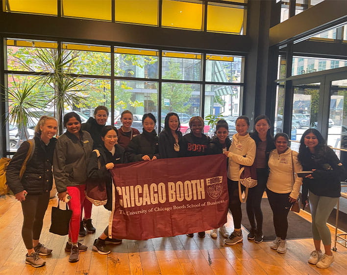 members of Graduate women in business posing with Chicago Booth flag