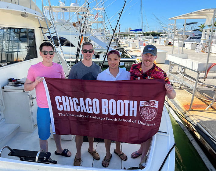 Dave Lam on boat with other Boothies holding up Booth flag