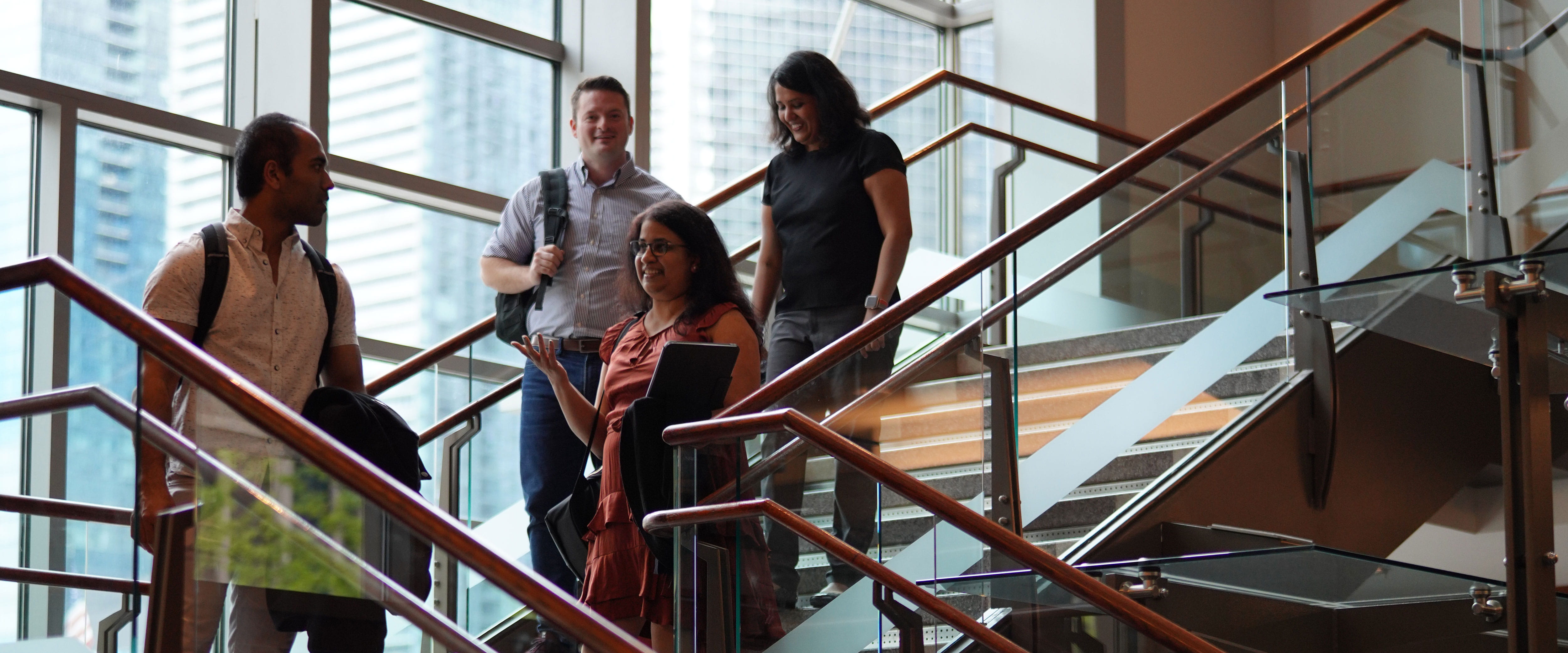 Group of four Evening/Weekend Students coming down the stairs at the Gleacher Center