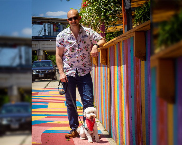 Brian and his dog photographed outside in front of colorful wall