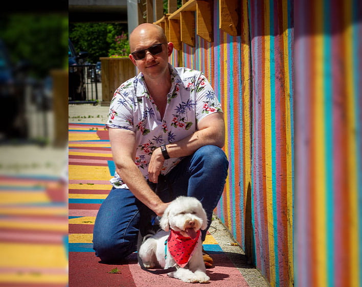 Brian and his dog photographed outside in front of colorful wall