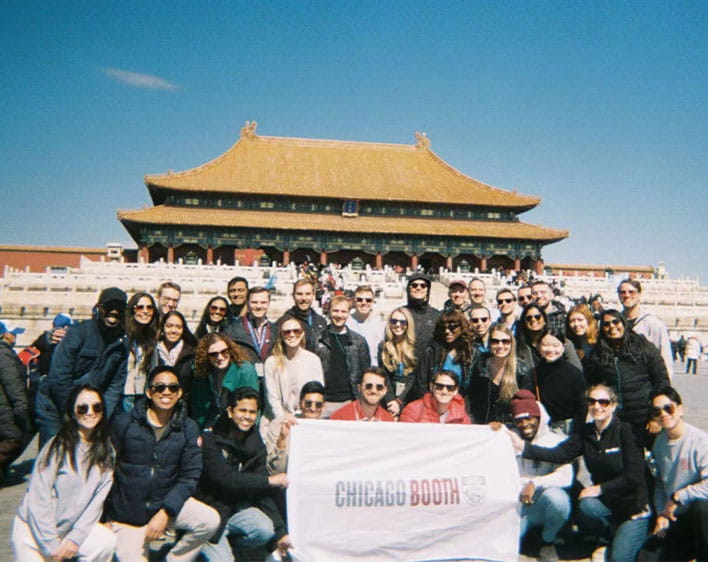 group photo of Michael and other Boothies on trip holding Booth flag