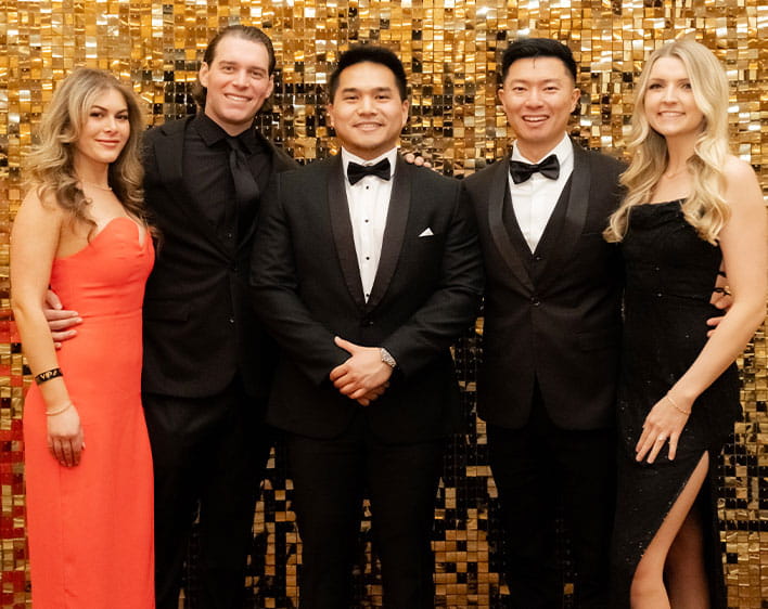 Lawrence, his wife, and friends in formal clothing in front of gold backdrop