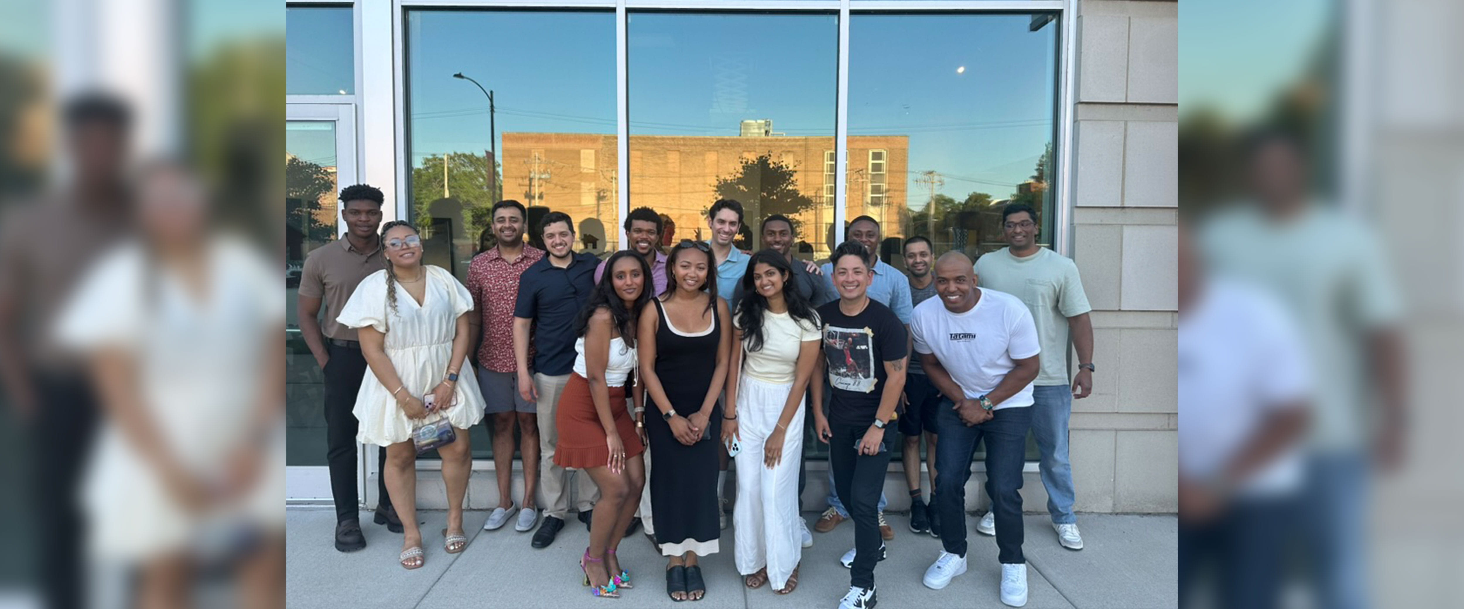 group photo of Maleek Thomas and other Boothies standing outside with window in background