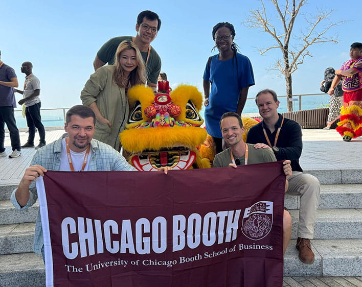 Group photo of Jacob Peterson and fellow Boothies in Hong Kong holding Booth flag