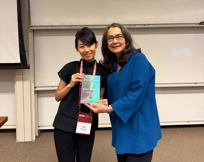 Ami Hamamoto and Professor Ginzel holding a book together while smiling in the classroom