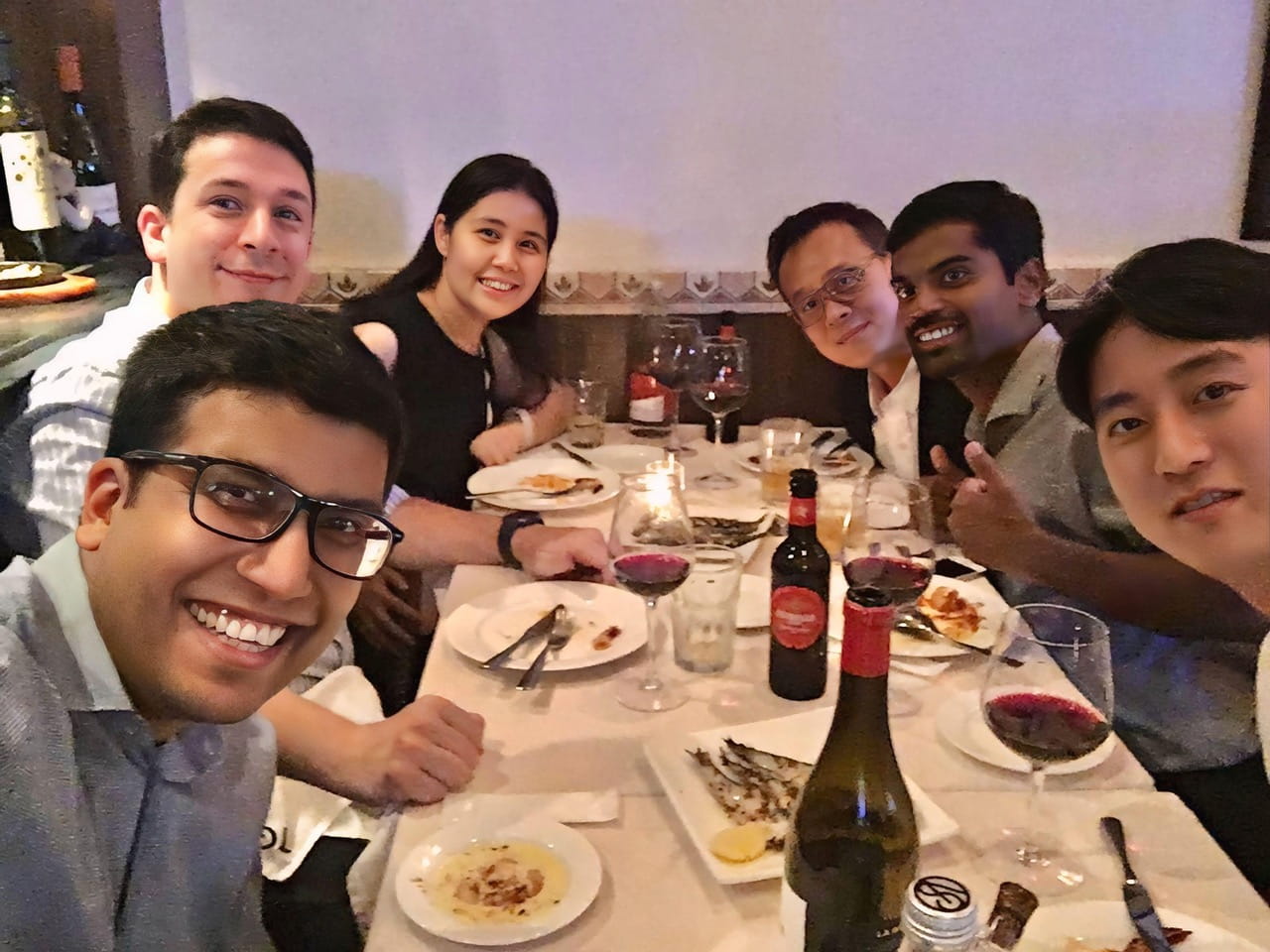 Several people sitting around a table, smiling for the camera