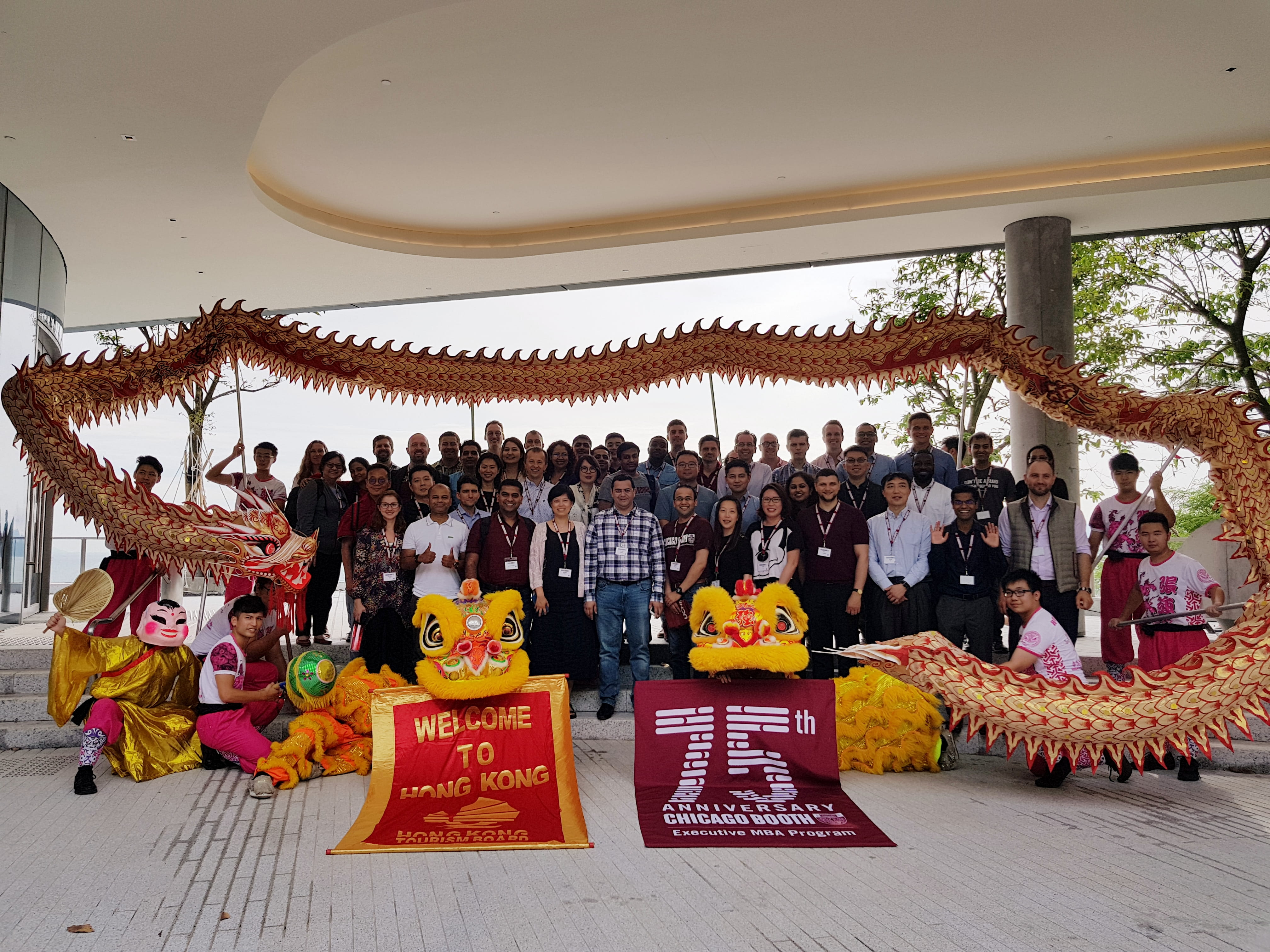 Group of students smiling, welcomed to Hong Kong campus with a traditional Chinese Lion Dance