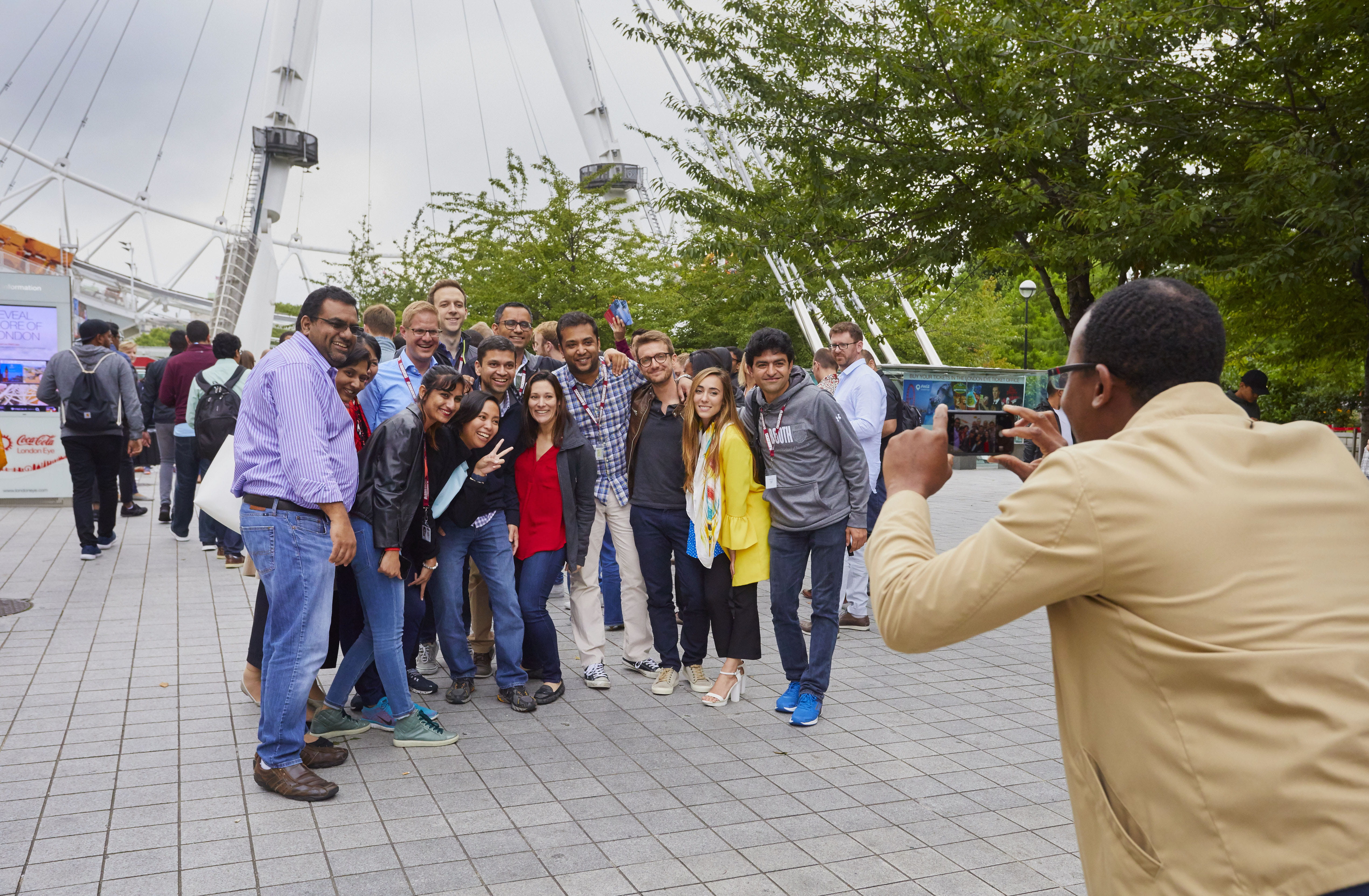 A group of Booth students pose for a photo in front of the London Eye Ferris wheel