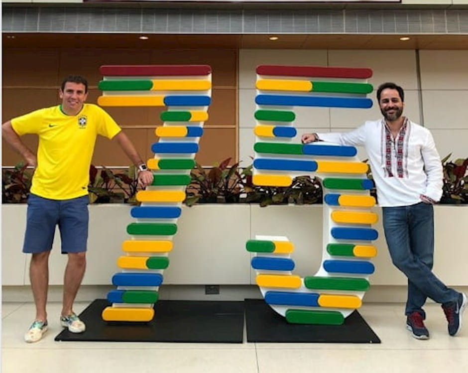 Two Executive MBA alumni stand on either side of number 75 sculpture
