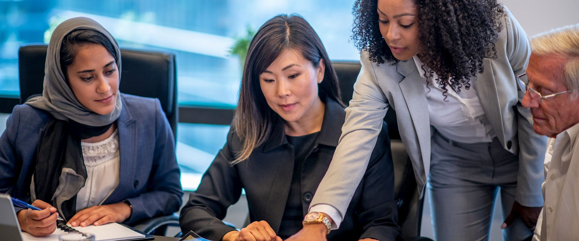 Women in business suits engaged around a document on the table