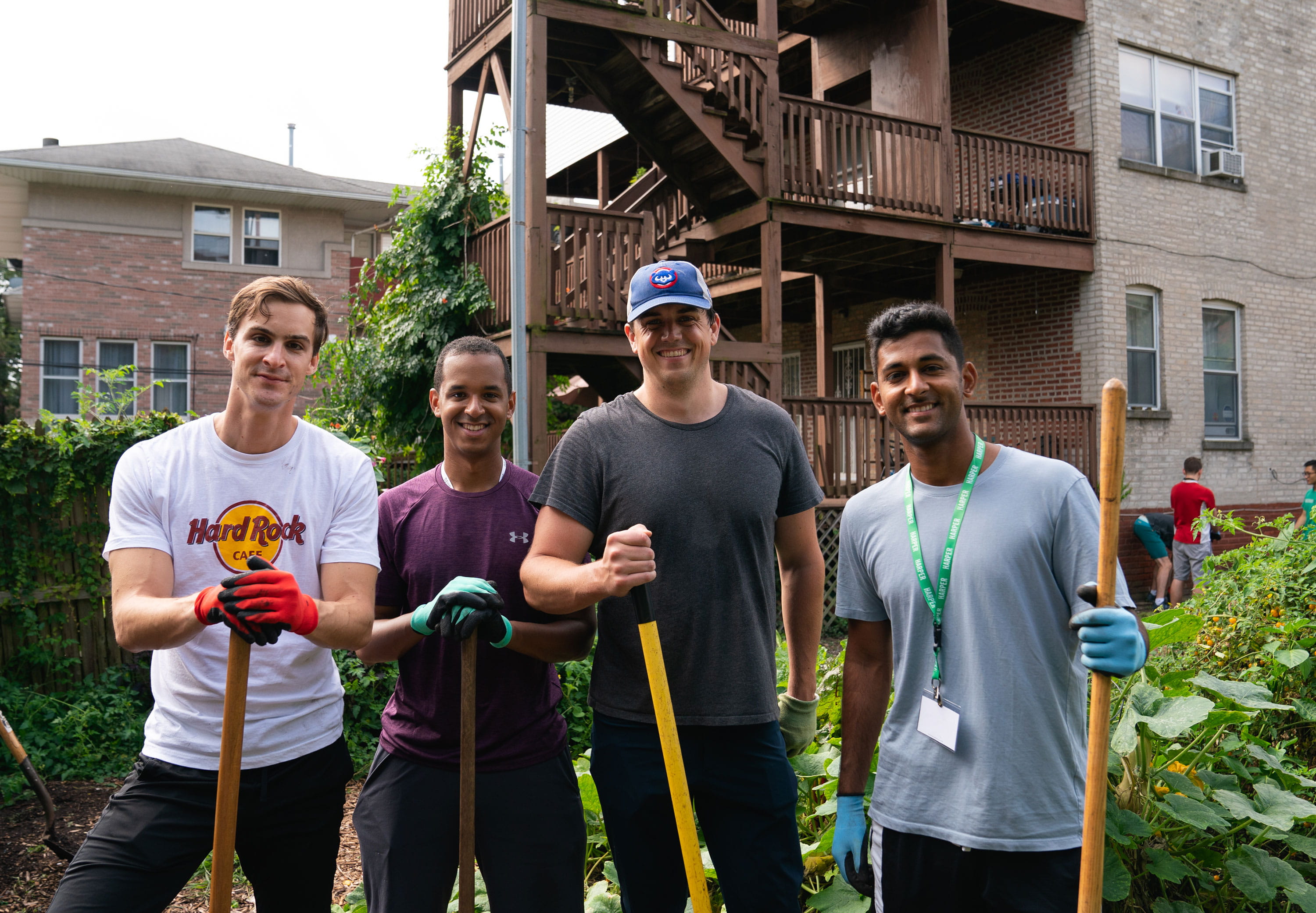 Male students outside smiling, holding shovels doing gardening work