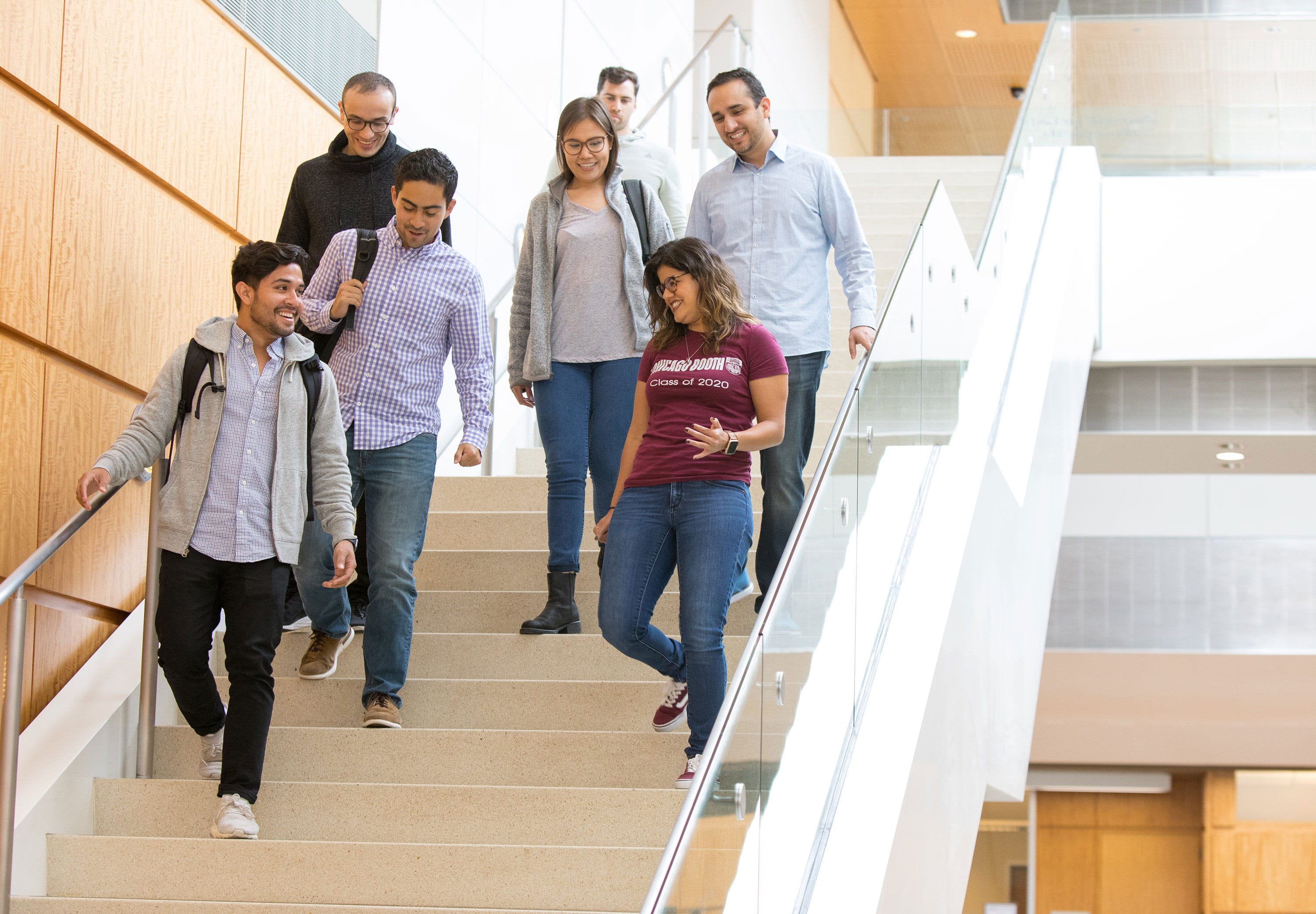 A group of students walks and talks down the stairs at the Harper Center