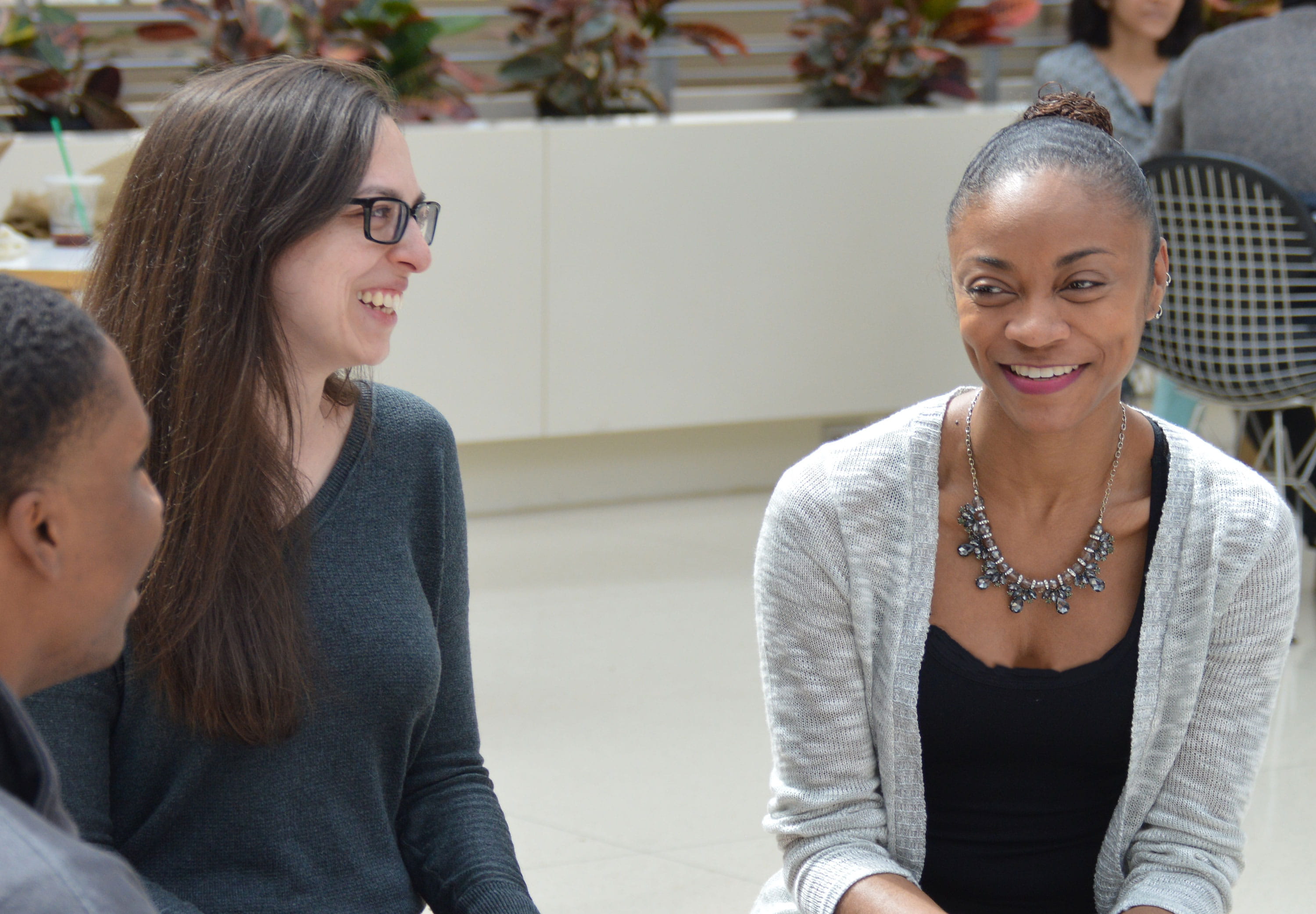 A group of alumnae smiling and conversing in the Harper Center's Winter Garden