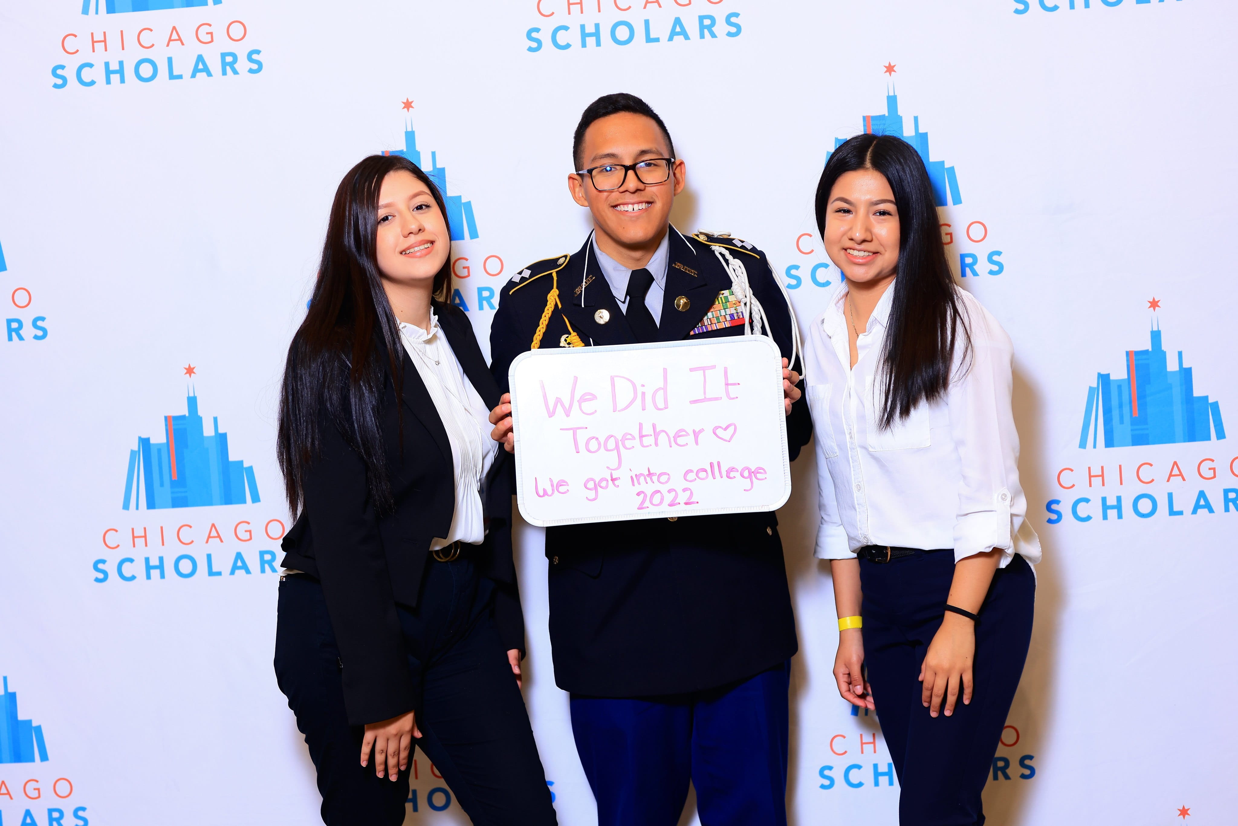 Three Chicago Scholars Students smiling in front of CS banner