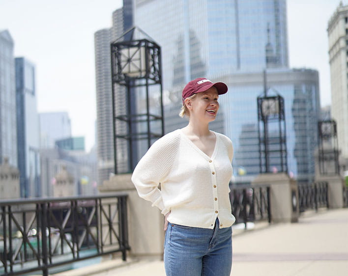 Booth student with Chicago Booth baseball cap on outside downtown Chicago