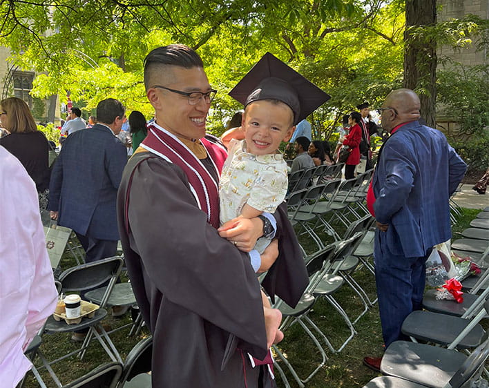 Jeff holding his son outside after graduation 