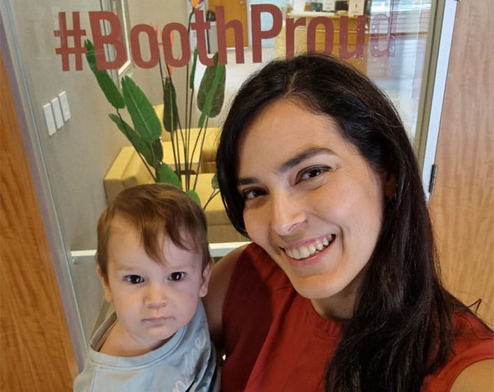 Naama posing with her child in front of #BoothProud sign