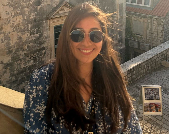 Maria Isabel Aguayo posing on rooftop of building with sun beaming in background