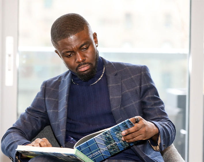 Prince Akonor Asare looking at book while sitting down