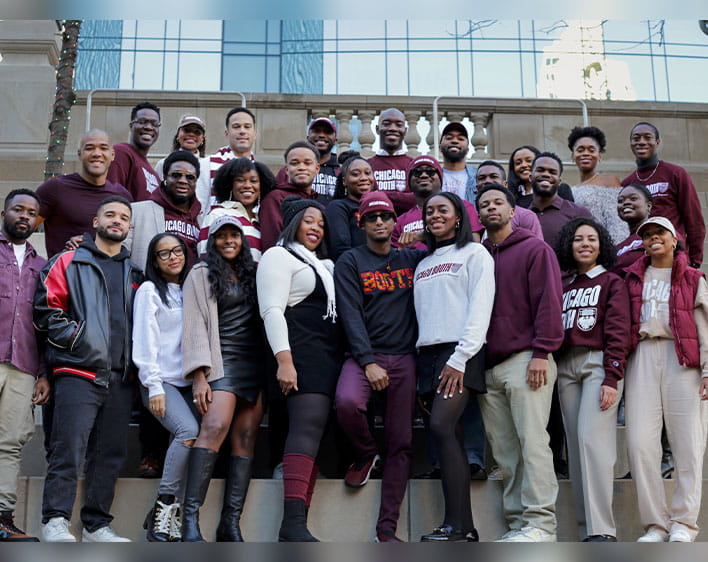 Tosan pictured with group of Boothies outside in Chicago Booth gear