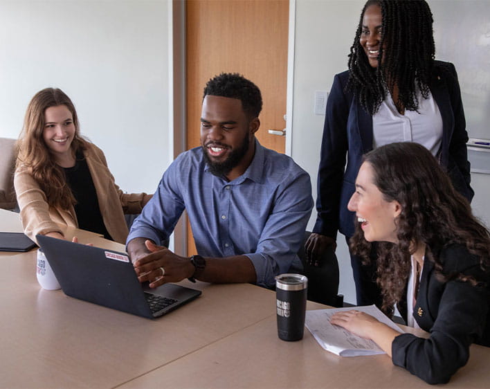 Tosan on computer with three other individuals surrounding him