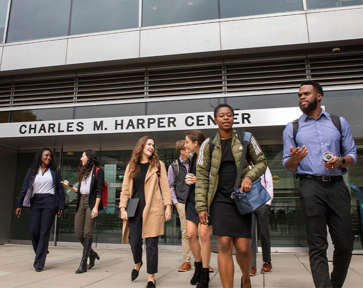 Tosan walking outside Harper Center while talking to another student with a few other students in the background