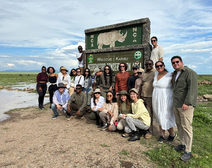 Group of Boothies pictured in nature in front of "Welcome Karibu" sign