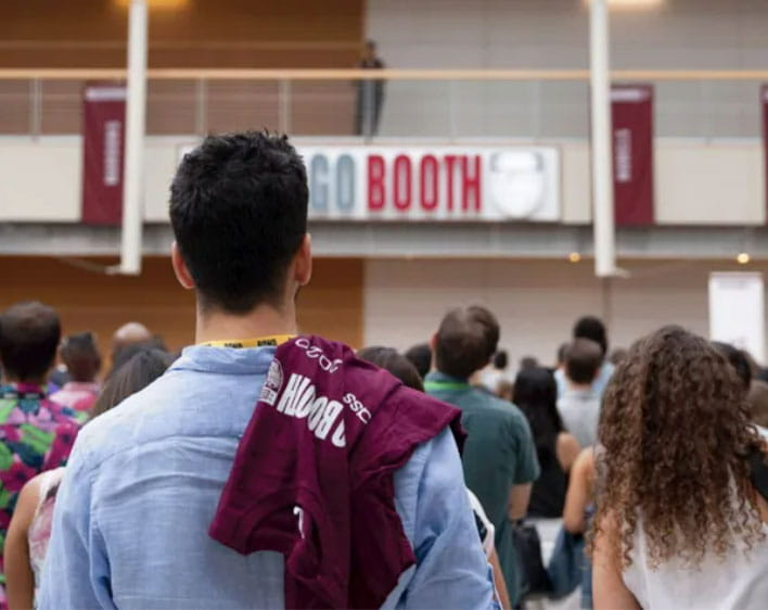 Student looking at Chicago Booth sign in crowd with Booth shirt hanging from shoulder