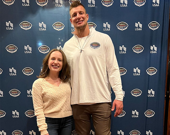 Emma and another individual posing in front of USAA banner