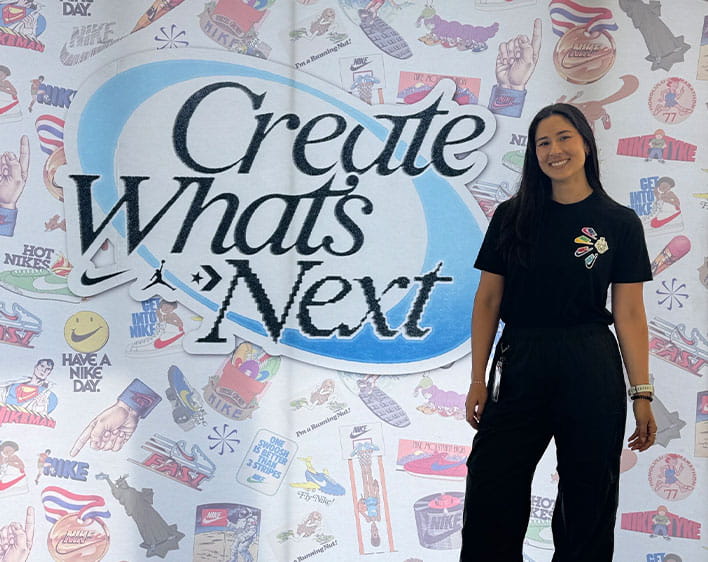 Natalie in front of a backdrop saying "Create What's Next" from her Nike internship