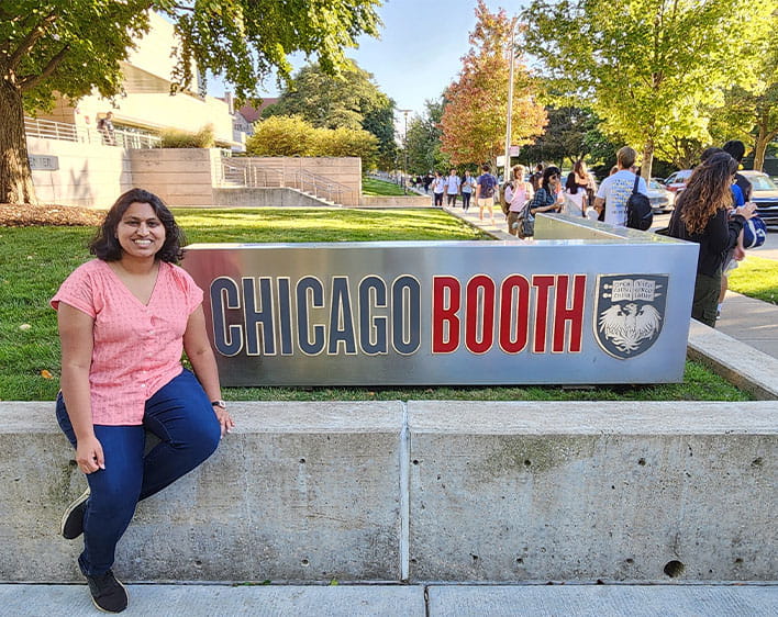 Isha in front of Chicago Booth sign at Harper Center