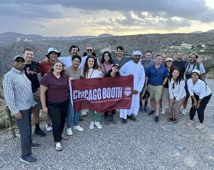 group of students at international trip outdoors holding up Booth flag