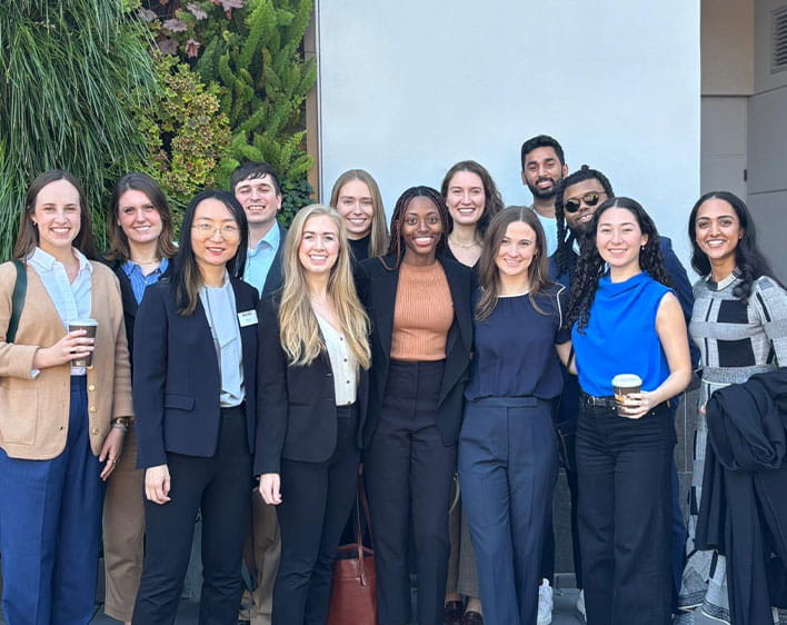 Rianna and a group of individuals all in professional work wear outside smiling