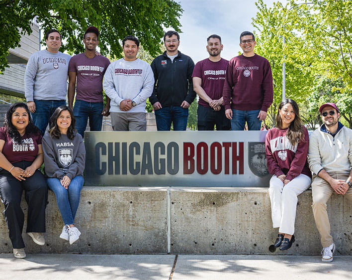 ten HABSA student group memebers seated and standing around Chicago Booth sign with Booth t-shirts and sweaters on