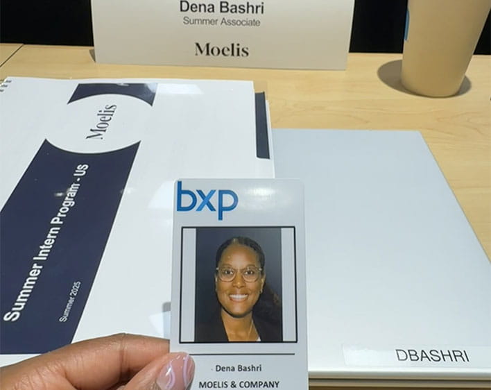 Dena's ID from her summer internship at Moelis with her name tent in background