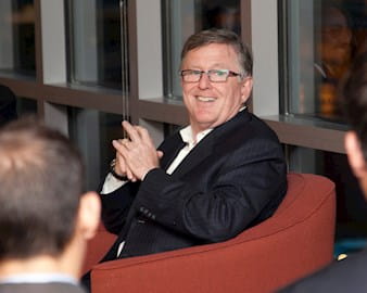 David Booth seated in front of the window at Gleacher during an event
