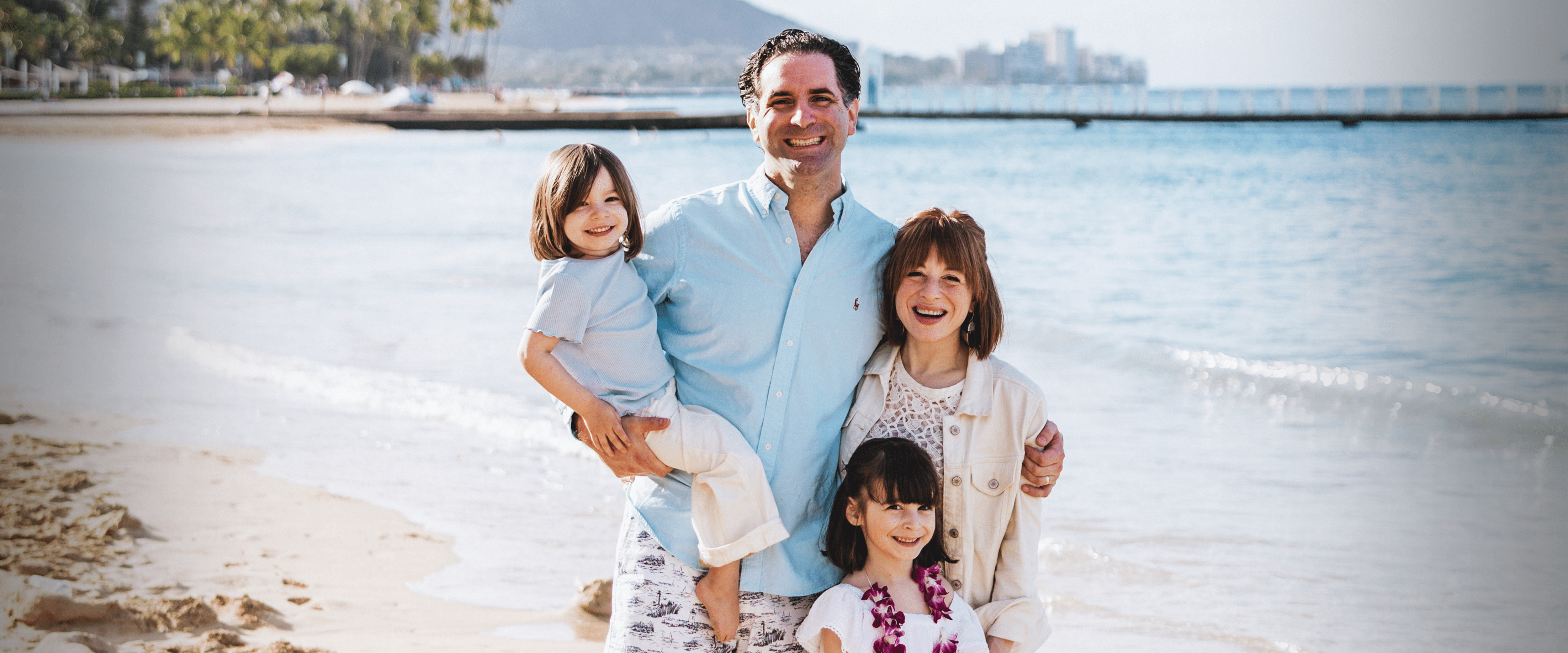 Alumnus Mike Larrenaga and his family standing on a beach.