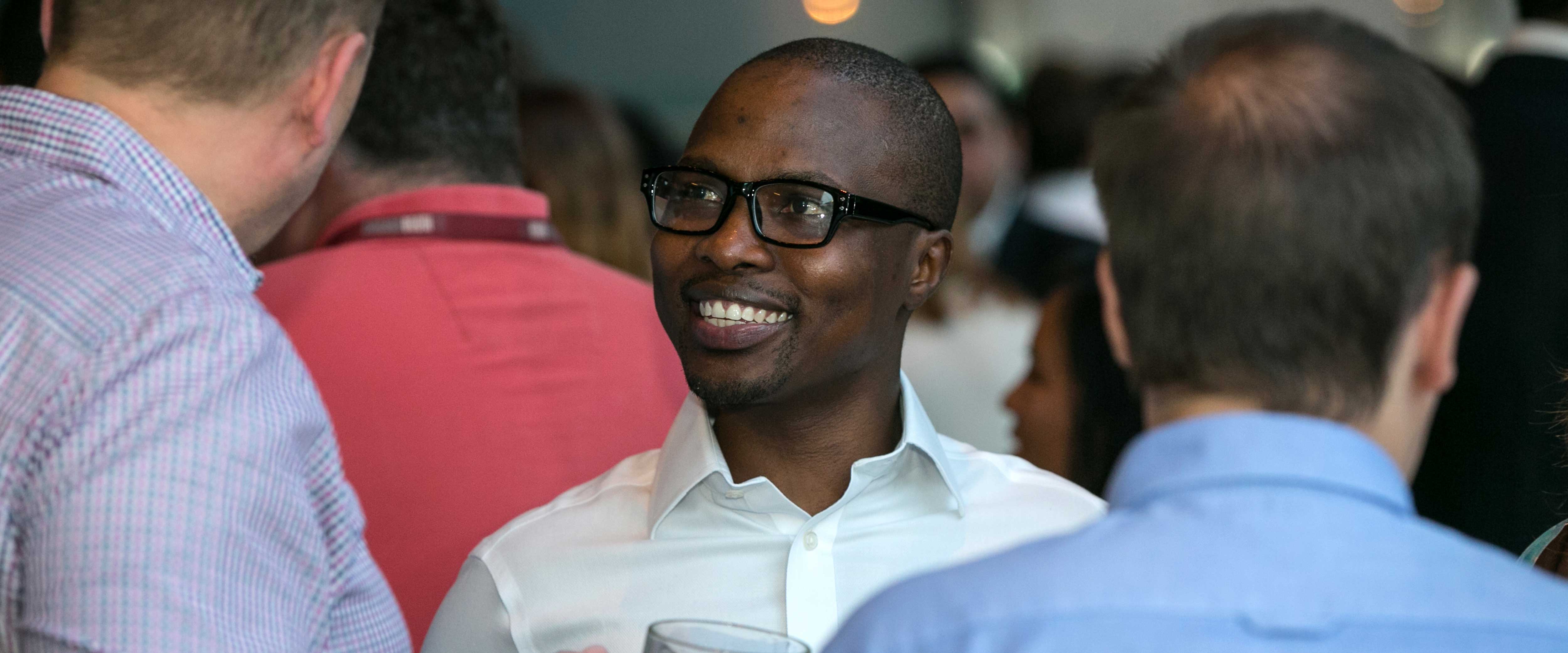 Man networking and smiling at the person he is speaking to