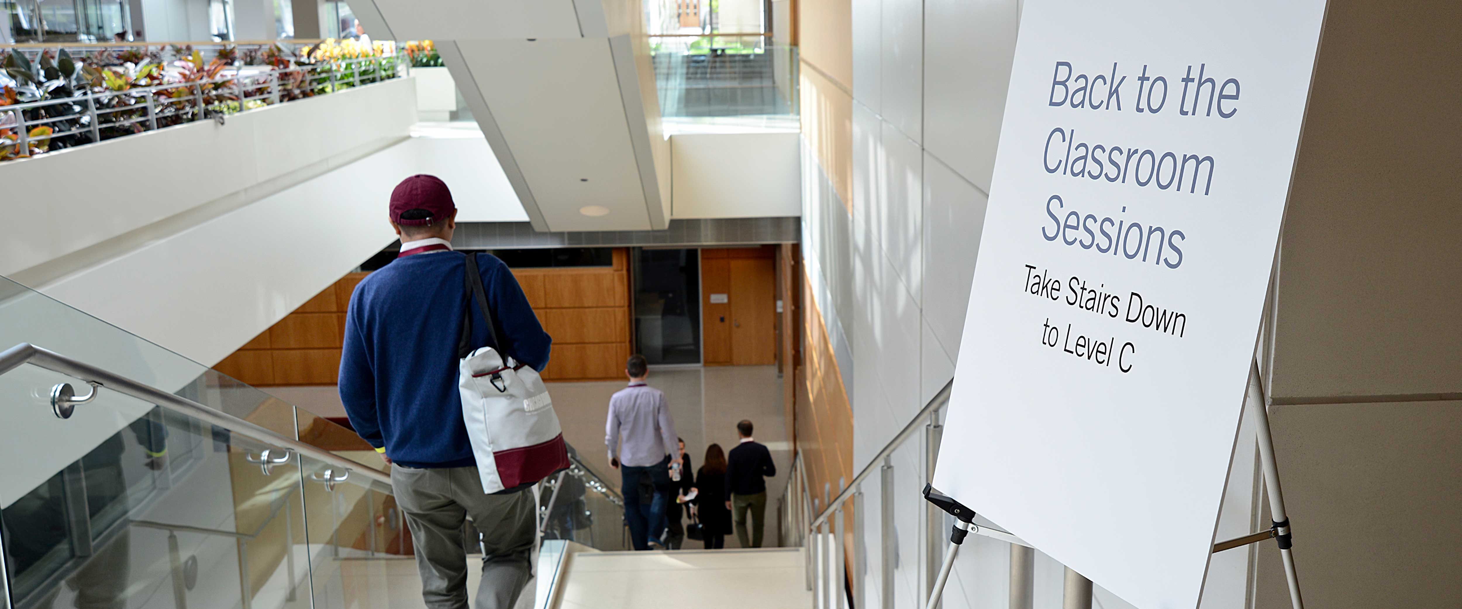 Man walking downstairs past a “Back to the Classroom Sessions” sign in the Harper Center 