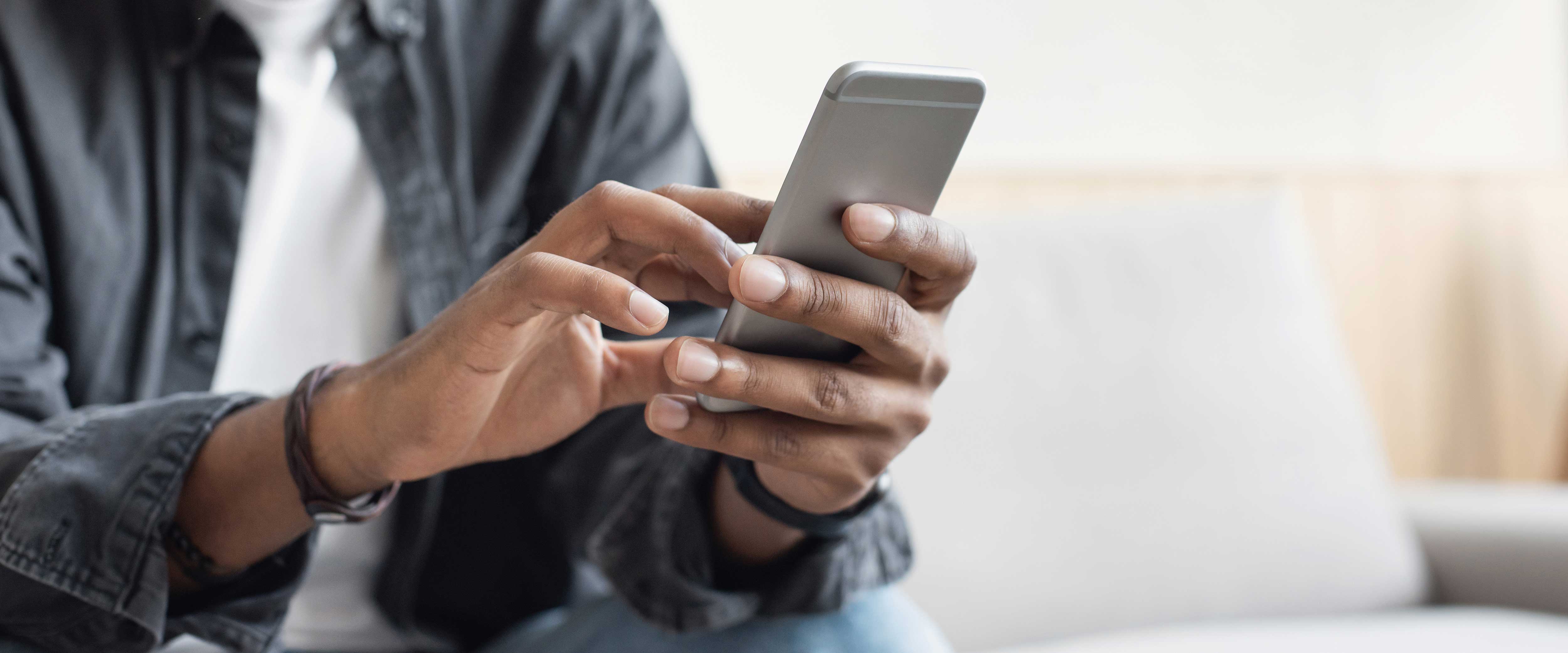Man's hands typing on a cell phone